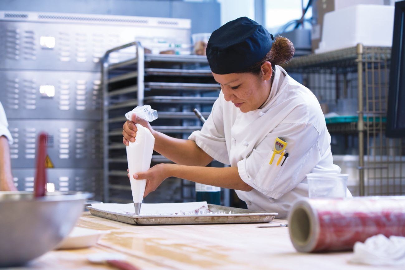 A culinary student using a piping bag